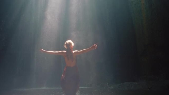 快乐的女人在瀑布洞穴里跳舞泼水穿着漂亮的衣服享受自然舞蹈感受精神自由4k