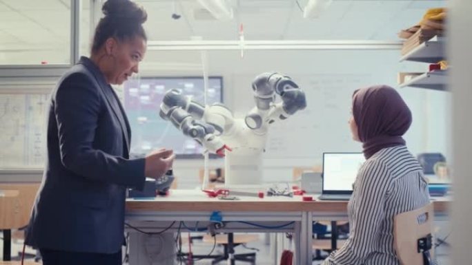 阿拉伯未来工程师在开发自动机器人系统程序时询问女教授。黑人妇女操纵机械臂。自主设施优化概念