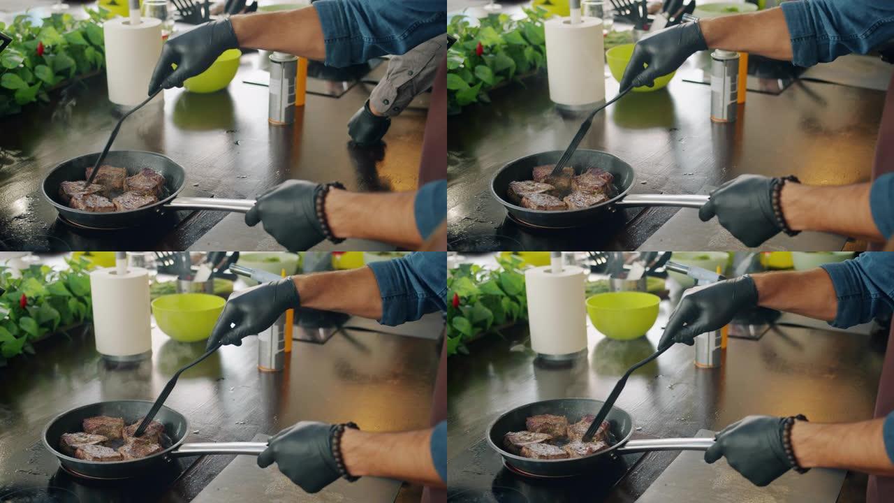 男厨师在厨房炊具上的煎锅做肉菜的特写