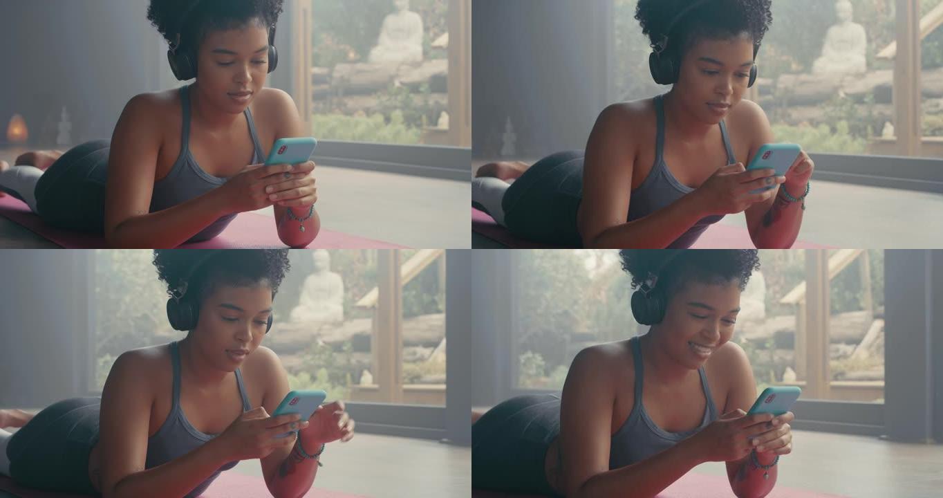 一名年轻女子在瑜伽期间使用智能手机和耳机的4k视频片段