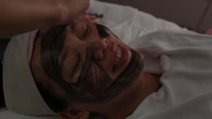 亚洲中国女性在床上躺着的面部水疗美容护理中的应用