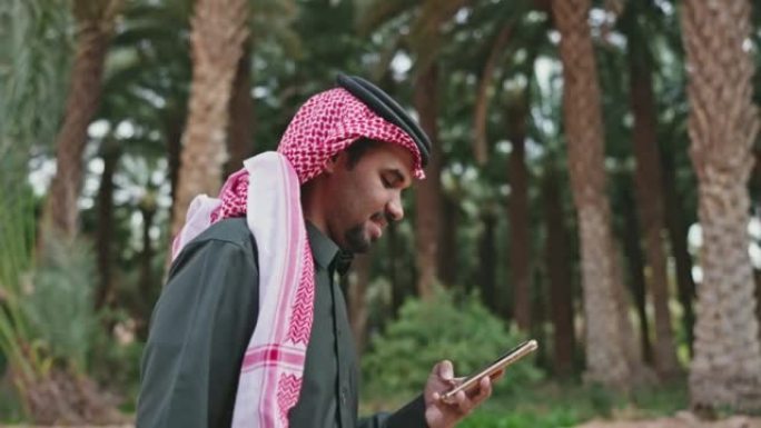 20多岁的沙特男子走路和使用电话