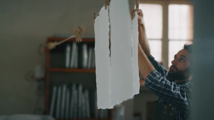 工匠造纸大师的慢动作正在车间里干燥高质量的手工纸。以8K拍摄。手工制作的概念，高品质，工匠，意大利制