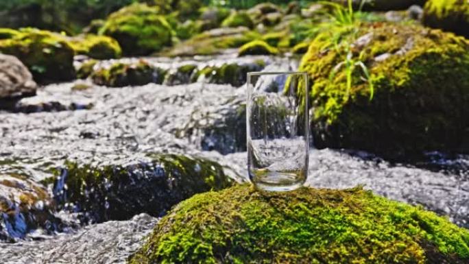 SLO MO空的水杯在岩石上覆盖着苔藓，在汹涌的溪流中