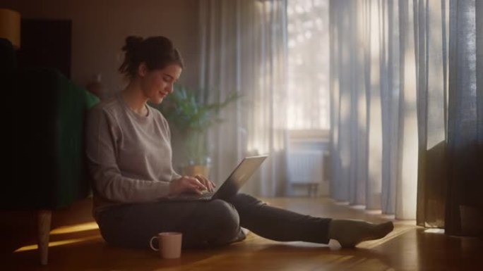 美丽的幸福女人在家使用笔记本电脑进行远程工作。年轻的成年微笑女人坐在地板上使用互联网，撰写报告，完成