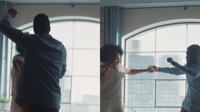 激动的恋爱中的年轻夫妇的电影垂直镜头进入框架，并开始在客厅中间跳舞。拥有快乐年轻人的明亮现代家园。慢