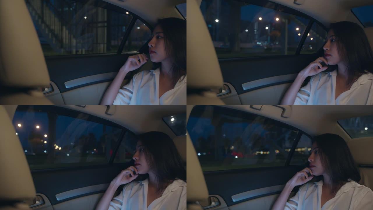 穿着时尚办公室服装的亚洲女商人晚上坐在城市现代的乘客后座上，看着窗外的车。