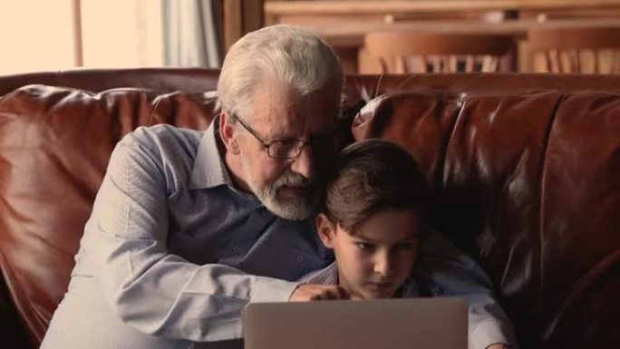 快乐的老爷爷和小孙子一起用电脑。