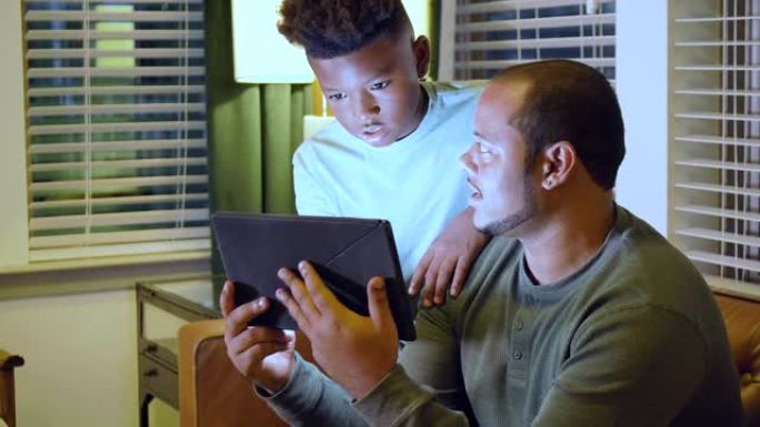 多种族男孩和继父看着数字平板电脑