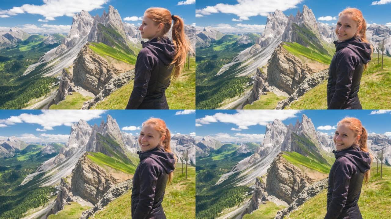 年轻的女徒步旅行者从意大利多洛米蒂的塞塞达山顶欣赏壮丽的景色，对着镜头微笑