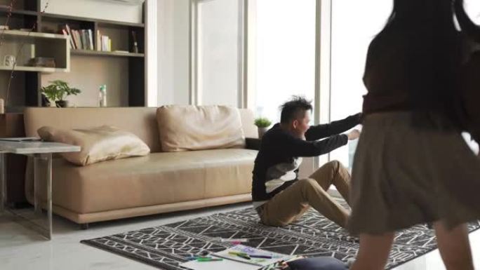 亚洲华人2父母在客厅里和孩子在家里玩耍，拥抱坐在地上