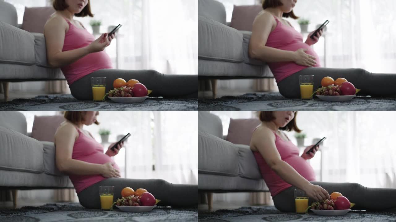 孕妇在家用手机吃水果在客厅放松