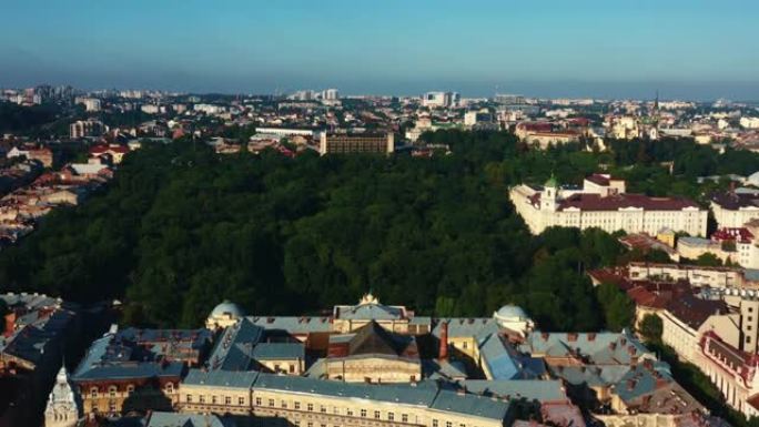 宁静的夏季日出时，乌克兰利沃夫老城美丽郁郁葱葱的绿色公园树木的雄伟空中背景。