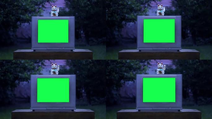 Maneki Neko幸运猫在绿屏的旧电视上。夜色。放大镜头。