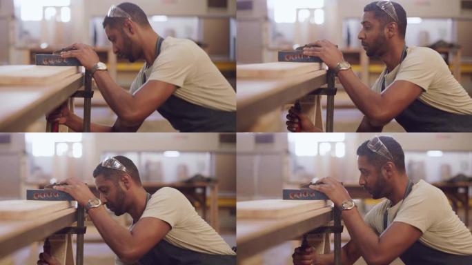 一名年轻男性工人在工作前在木桌上使用夹子的4k录像