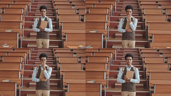 站在演讲厅的眼镜中不安全的混血学生