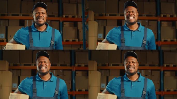 英俊的黑人男性工人的肖像拿着纸板箱站在仓库里满满的货物。快乐专业在物流配送中心工作，在线交付电子商务