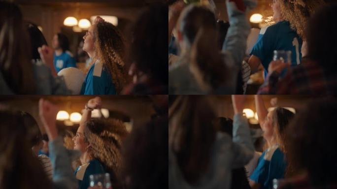 一位穿着蓝色球衣的多民族年轻女性的肖像在酒吧里的一群体育迷中欢呼，看电视转播。当球队进球并赢得比赛时