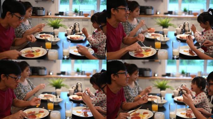 有两个孩子的亚洲中国年轻家庭周末早上在厨房一起吃早餐
