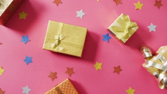 粉红色背景上的包装礼物和彩色星星的视频