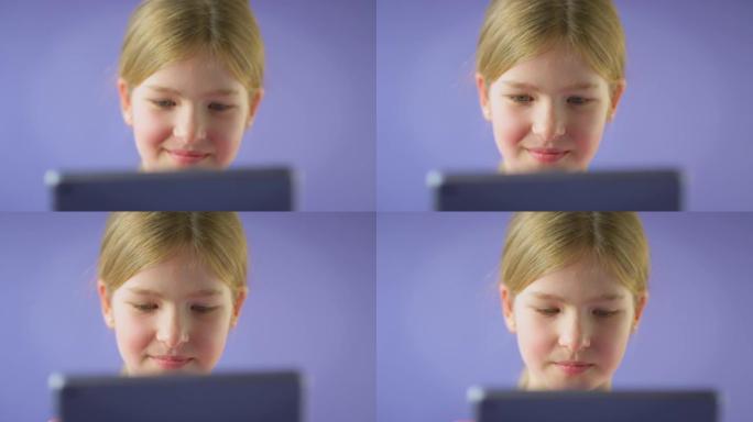在紫色工作室背景下使用数字平板电脑拍摄微笑女孩的工作室照片-慢动作拍摄