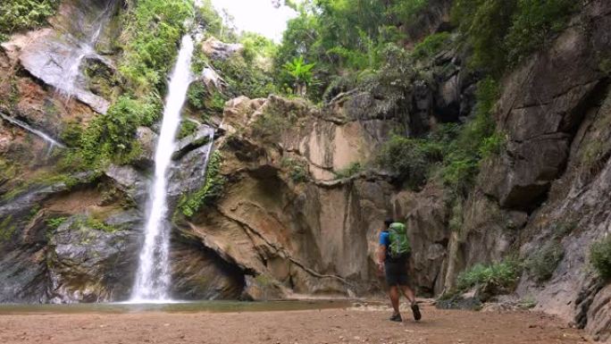 雄性徒步旅行者在雨林中徒步旅行在绿色森林中的小溪瀑布探险