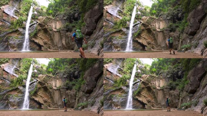 雄性徒步旅行者在雨林中徒步旅行在绿色森林中的小溪瀑布探险