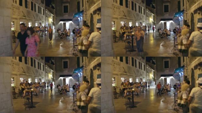 夏天晚上，人们在欧洲城镇的老中心散步的散焦镜头。街头咖啡馆有游客、交流、休息。舒适的浪漫氛围