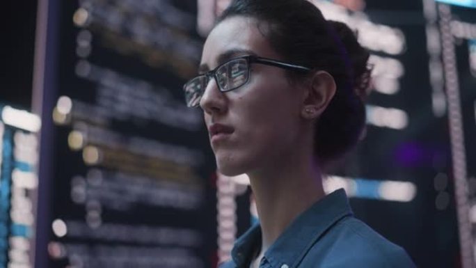 特写在电脑上工作的女人的肖像，从大屏幕上反射出她的眼镜上的代码语言。女程序员开发新软件，编码，管理网