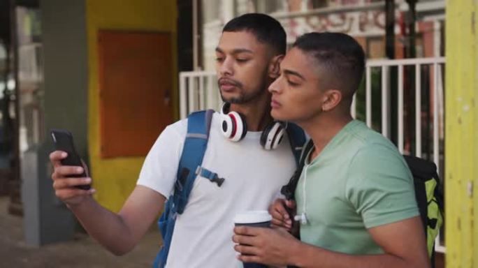 两个混血男性朋友在街上喝咖啡和使用智能手机