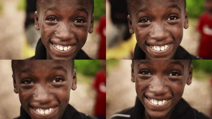 一个顽皮的真实的非洲孩子的特写肖像看着相机和微笑的强烈模糊的背景。快乐活力的黑人男孩与世界分享他美丽
