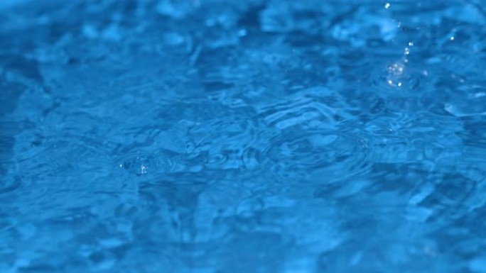 宏观，dop: 详细拍摄雨滴落入浅蓝色水池的照片。