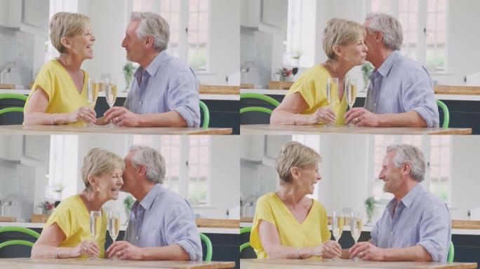 亲吻退休夫妇在约会之夜一起在家用一杯香槟庆祝