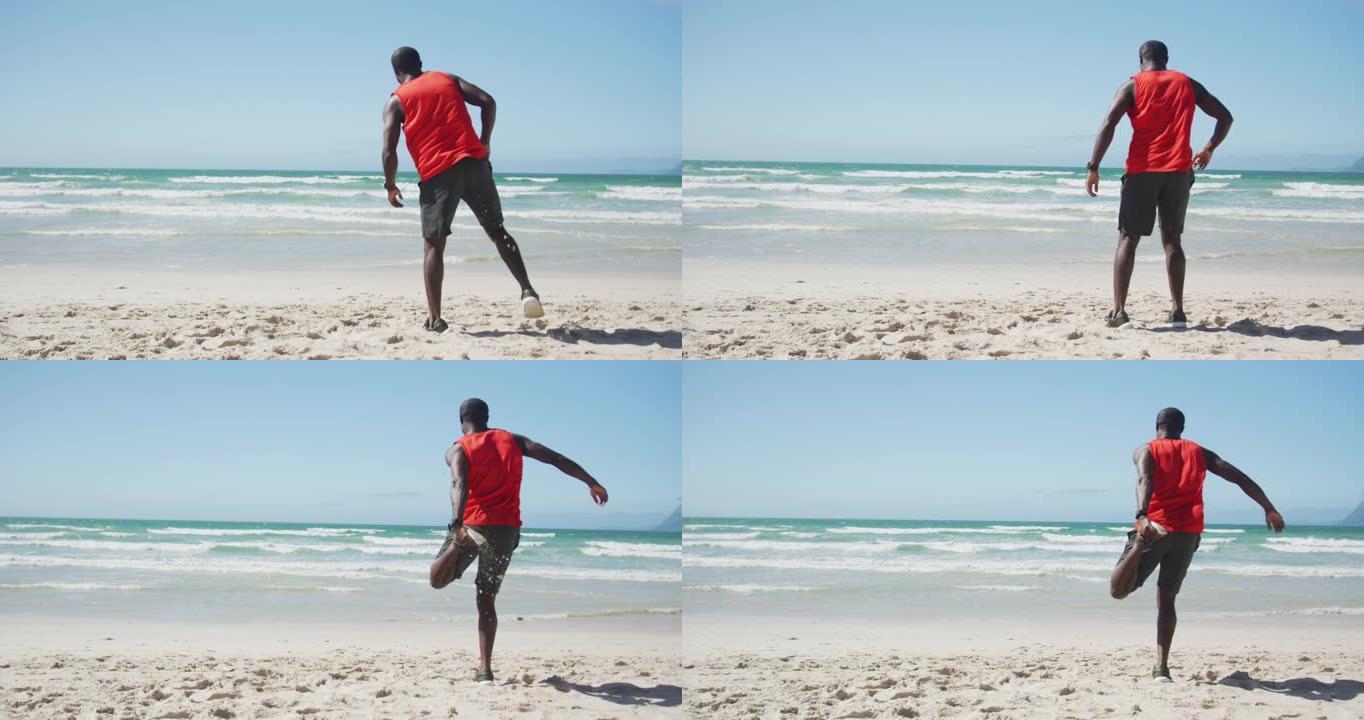 非裔美国男子在沙滩上伸展，在海边户外运动