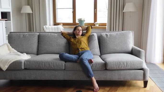 年轻女子在时尚布置的公寓里的沙发上放松