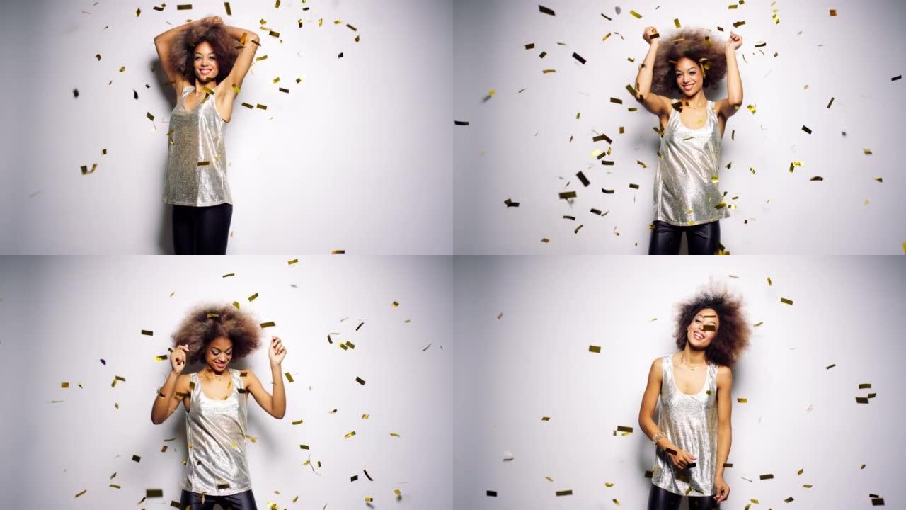 4k视频片段，一名年轻女子在工作室背景下跳舞，五彩纸屑掉落