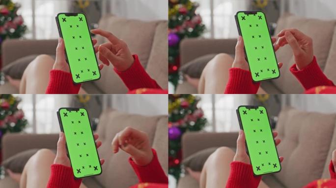 女人使用带有绿屏的智能手机，圣诞节网购的概念