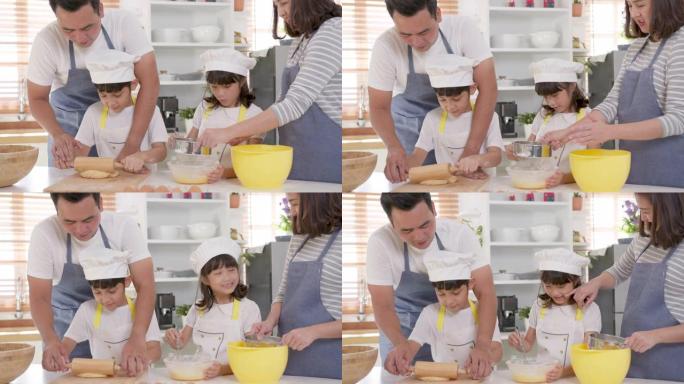 快乐的亚洲家庭父亲和母亲帮助小孩子的女儿和儿子的孩子在家里的厨房准备面包店。围裙的小孩在家里和父母一