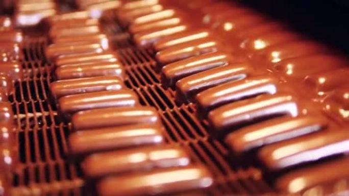 在生产过程中，成批的糖果被巧克力覆盖。带糖果的工厂输送机。