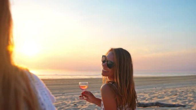 WS两个女人在日落时在沙滩上喝玫瑰酒很有趣