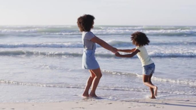 非裔美国母亲和女儿在海滩上玩耍