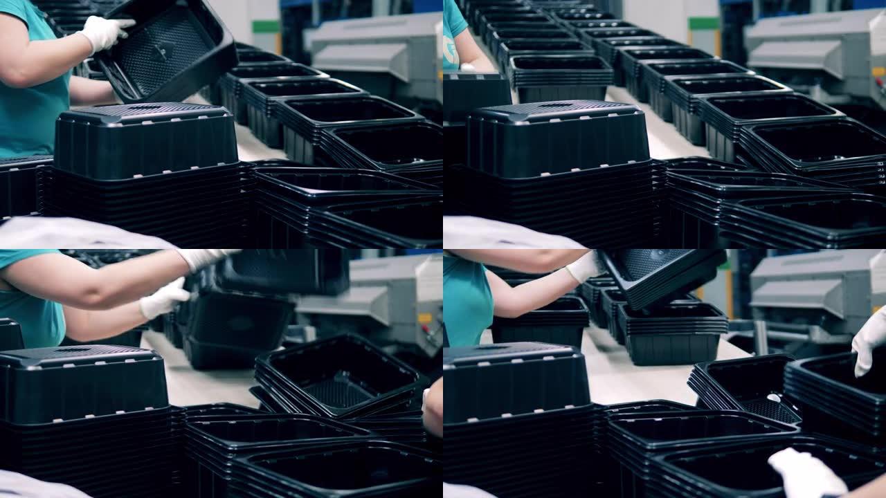 工人堆放黑色塑料容器从生产线上滚下