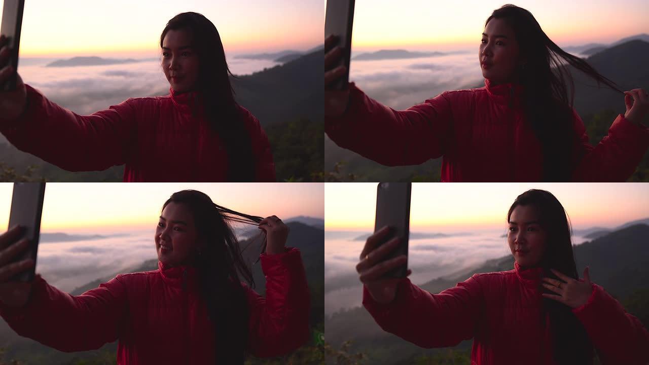 剪影年轻女子在山上用阳光和雾拍摄风景。独自旅行背包客带着相机徒步旅行。假日旅行和度假概念。