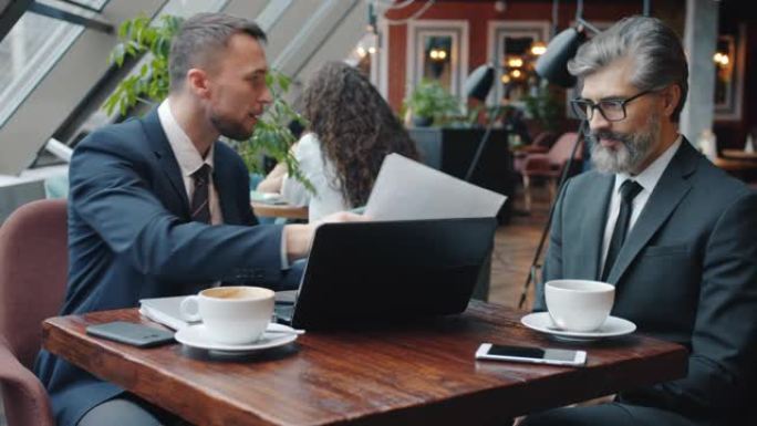 疯狂的商人与在咖啡馆使用笔记本电脑持有合同的合伙人争论