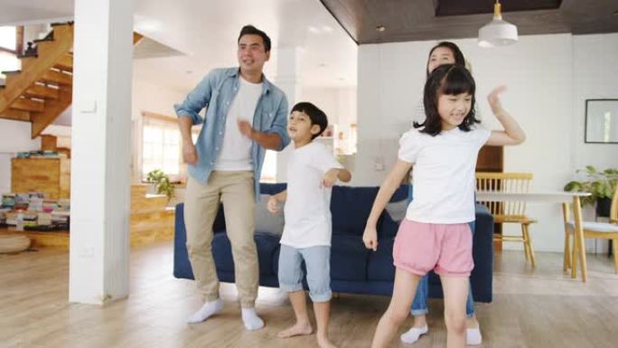 慢动作 -- 快乐的亚洲家庭在现代家庭的客厅听音乐和跳舞。