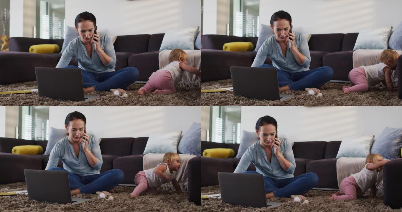 白人母亲在家里的地板上爬行时使用笔记本电脑并在智能手机上聊天
