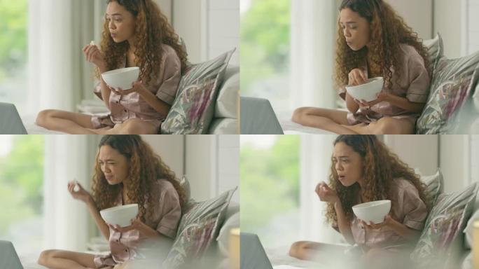 4k视频片段，一名年轻女子使用笔记本电脑并在家中床上吃爆米花
