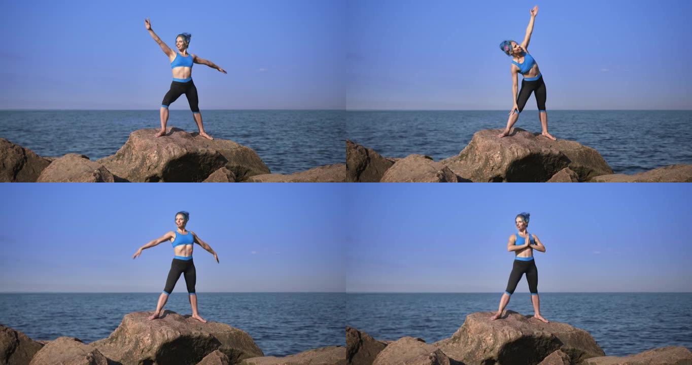 一位拥有绿松石头发的健康美丽的瑜伽老师正在做练习，站在石头上靠着大海和天空，