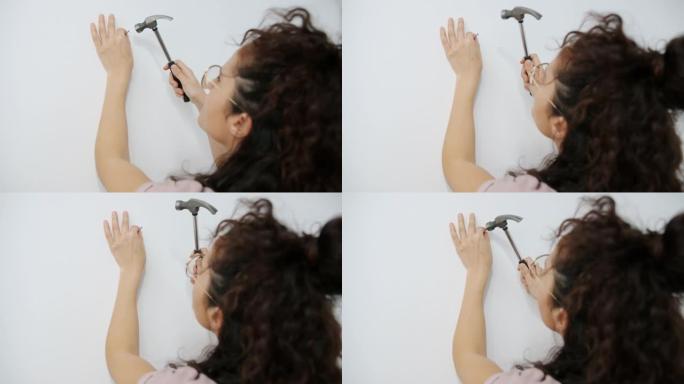 女性双手在墙上敲钉子的特写镜头独自在家工作