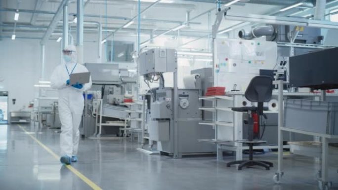 重工业制造工厂:科学家在无菌工作服与笔记本电脑行走，检查工业数控机床设置和配置生产功能。